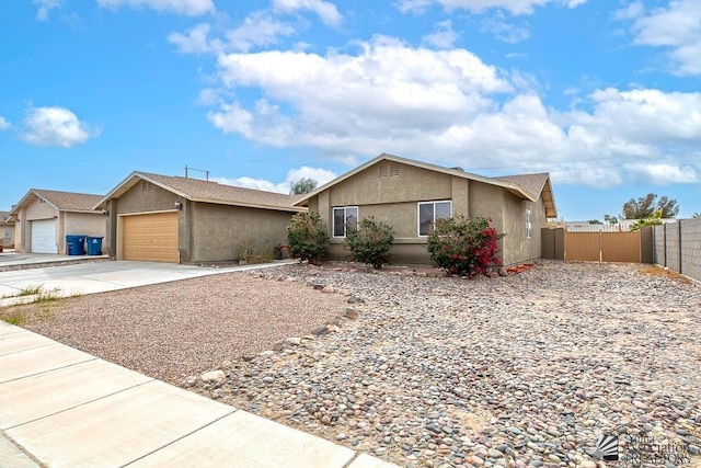 ranch-style house featuring a gate, fence, concrete driveway, and stucco siding