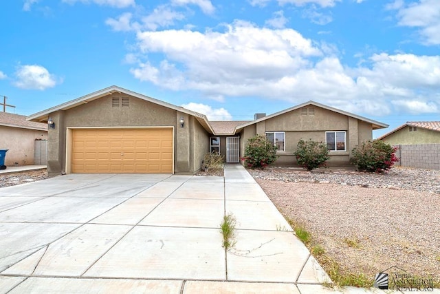 ranch-style house with driveway, an attached garage, fence, and stucco siding