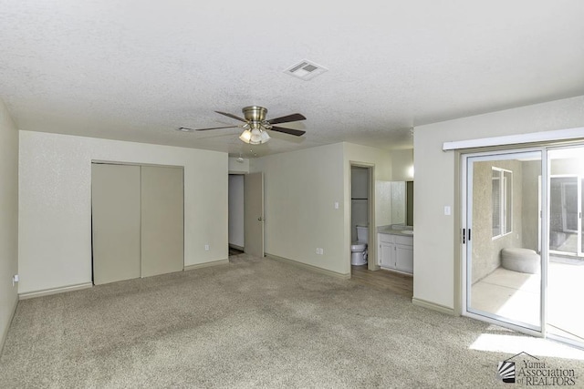 unfurnished bedroom with access to outside, light carpet, visible vents, and a textured ceiling