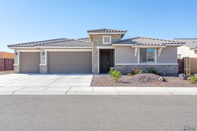 view of front of property featuring stone siding, an attached garage, fence, and stucco siding