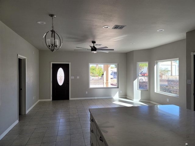 tiled foyer entrance featuring ceiling fan with notable chandelier