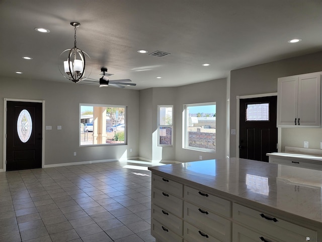 tiled entryway featuring ceiling fan with notable chandelier