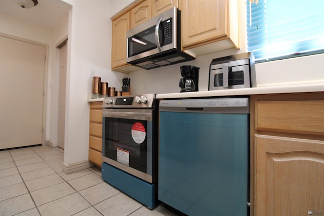 kitchen featuring appliances with stainless steel finishes, light tile patterned floors, and light brown cabinetry