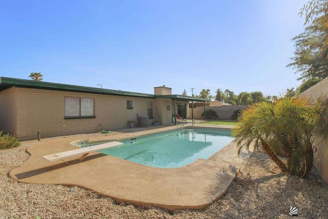 view of swimming pool featuring a patio, a diving board, and central AC