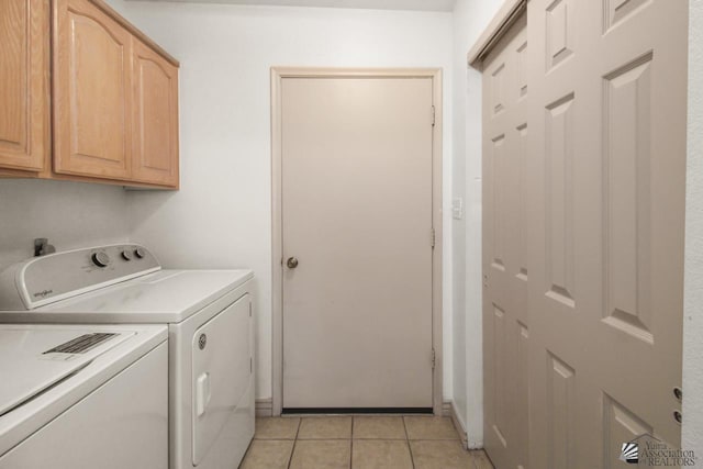 clothes washing area with washer and dryer, light tile patterned floors, and cabinets