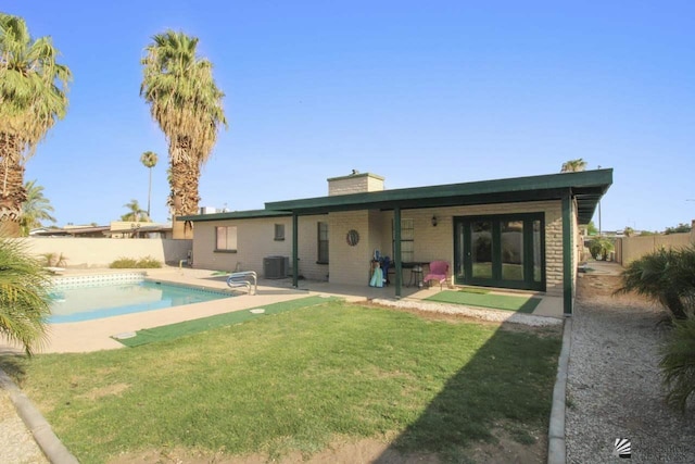 back of property featuring central AC unit, a patio area, a fenced in pool, and a yard