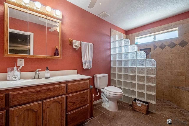 bathroom featuring vanity, tile patterned flooring, ceiling fan, toilet, and a tile shower