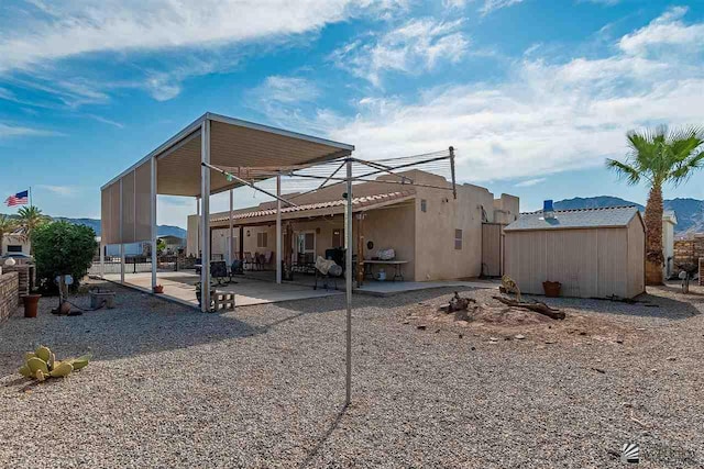 rear view of property with a shed and a patio area