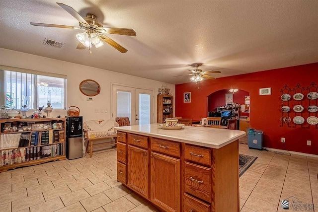 kitchen with french doors, a center island, a textured ceiling, and light tile patterned floors