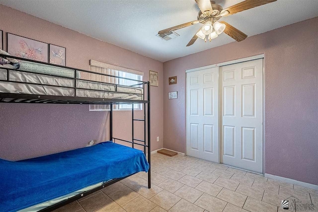 unfurnished bedroom featuring ceiling fan, a closet, light tile patterned floors, and a textured ceiling