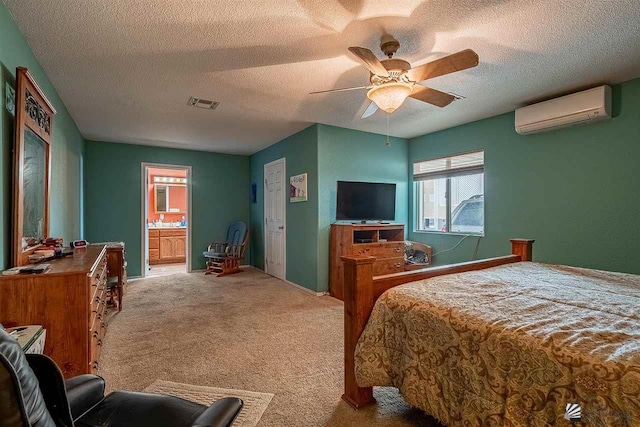 bedroom featuring ensuite bath, ceiling fan, a wall unit AC, light colored carpet, and a textured ceiling