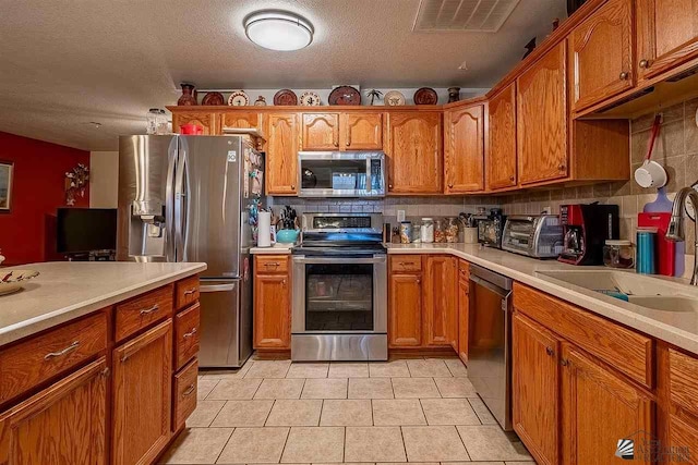 kitchen with backsplash, sink, stainless steel appliances, and a textured ceiling