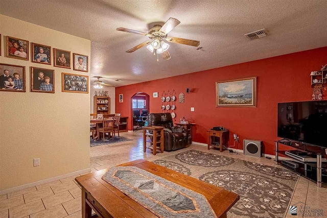 living room with ceiling fan, light tile patterned floors, and a textured ceiling