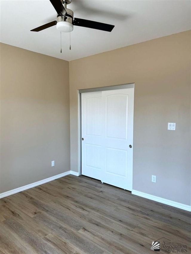 unfurnished bedroom featuring ceiling fan, dark hardwood / wood-style floors, and a closet