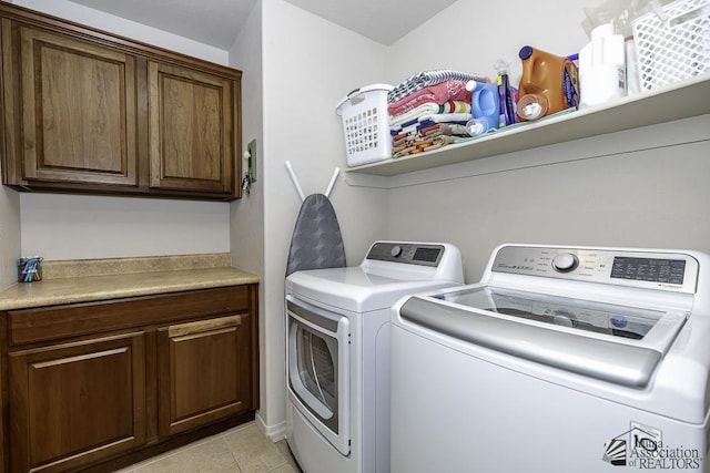 laundry area featuring cabinets, light tile patterned floors, and washer and clothes dryer