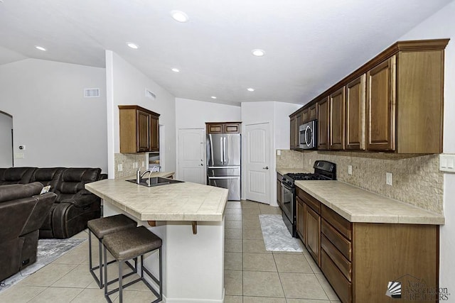 kitchen with sink, stainless steel appliances, kitchen peninsula, vaulted ceiling, and a breakfast bar area