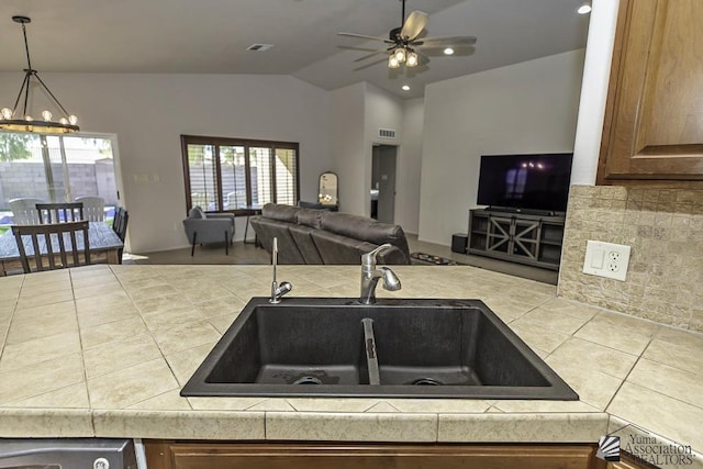 kitchen with ceiling fan with notable chandelier, lofted ceiling, and sink