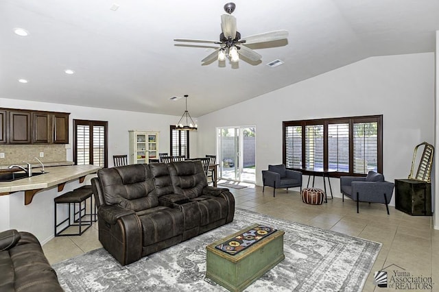 living room featuring ceiling fan with notable chandelier, sink, a wealth of natural light, and vaulted ceiling