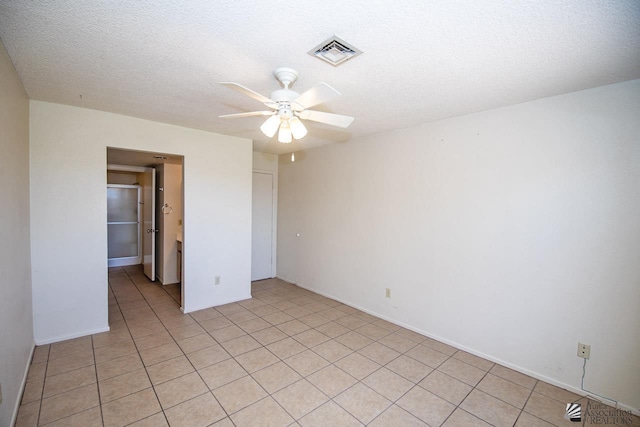 unfurnished room featuring a textured ceiling, ceiling fan, and light tile patterned flooring