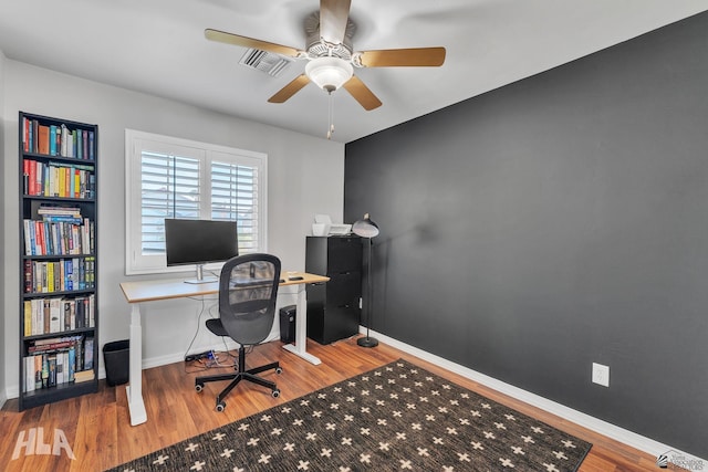 office featuring a ceiling fan, visible vents, baseboards, and wood finished floors