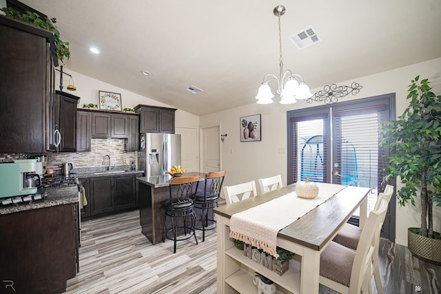 dining area featuring a chandelier, light hardwood / wood-style floors, vaulted ceiling, and sink