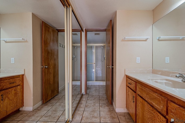 bathroom featuring vanity, an enclosed shower, tile patterned flooring, and a textured ceiling