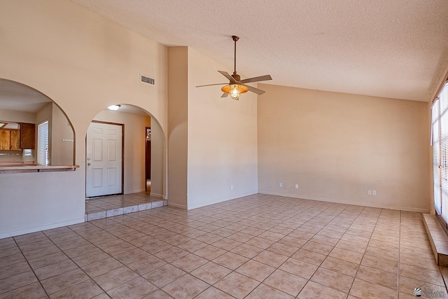 tiled spare room with a textured ceiling, high vaulted ceiling, and ceiling fan