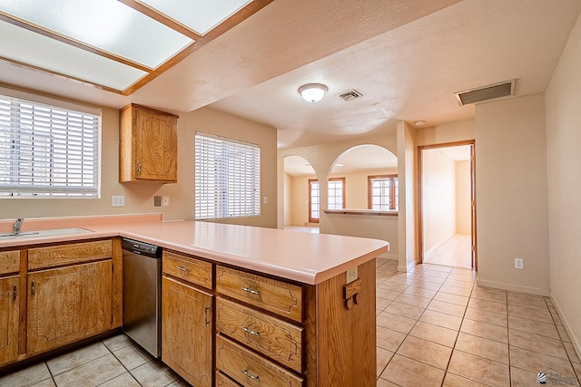 kitchen featuring stainless steel dishwasher, kitchen peninsula, sink, and light tile patterned floors