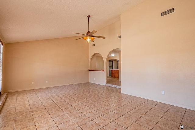 tiled empty room featuring ceiling fan, high vaulted ceiling, and a textured ceiling