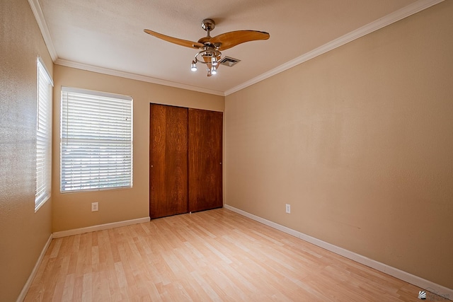 unfurnished bedroom with ceiling fan, ornamental molding, a closet, and light wood-type flooring