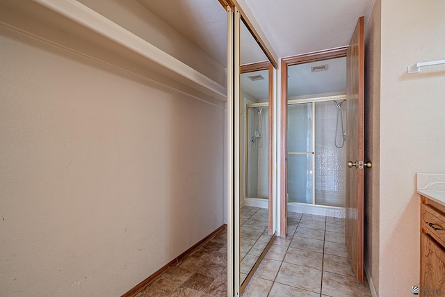 interior space with tile patterned flooring, vanity, and an enclosed shower