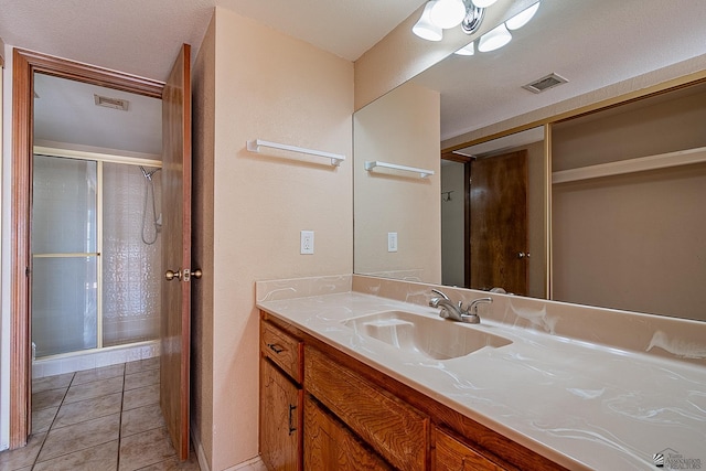 bathroom with vanity, a shower with door, and tile patterned flooring