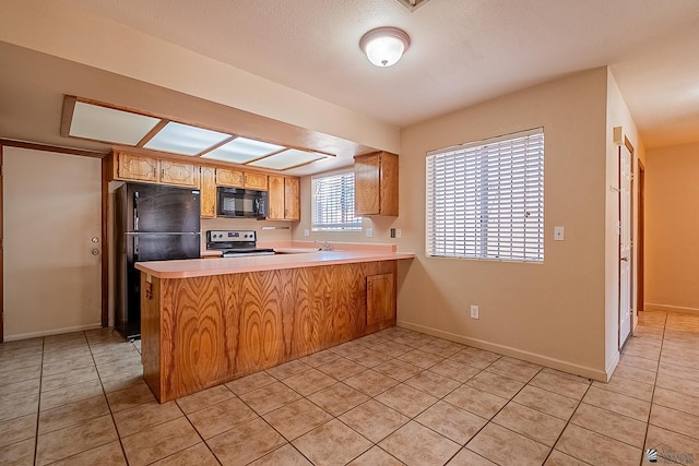 kitchen featuring kitchen peninsula, light tile patterned floors, and black appliances