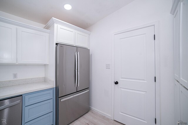 kitchen featuring light hardwood / wood-style floors, light stone counters, white cabinetry, and appliances with stainless steel finishes