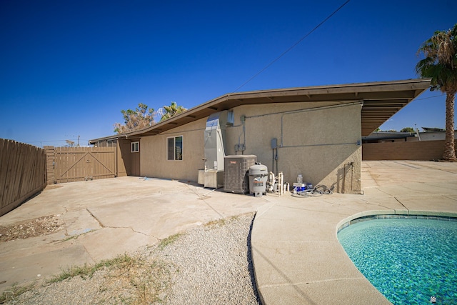 rear view of house with a patio, a fenced in pool, and cooling unit