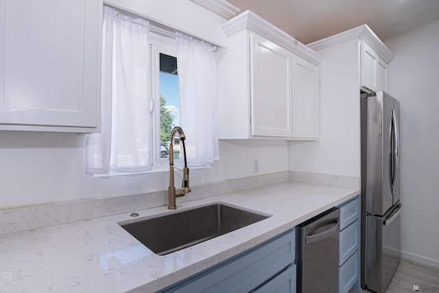 kitchen with white cabinets, light stone counters, sink, and stainless steel appliances