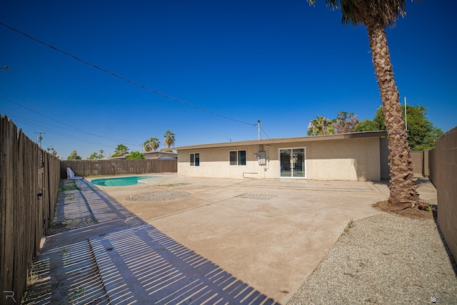 rear view of house featuring a fenced in pool and a patio area