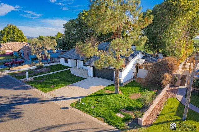 exterior space featuring a garage, driveway, fence, and a lawn