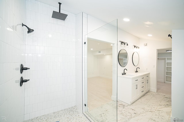 bathroom with tiled shower and vanity