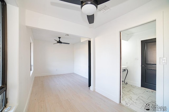 empty room featuring ceiling fan, marble finish floor, visible vents, and baseboards