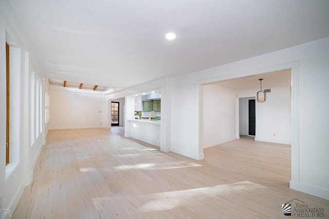 unfurnished room with recessed lighting, a sink, light wood-style flooring, and baseboards