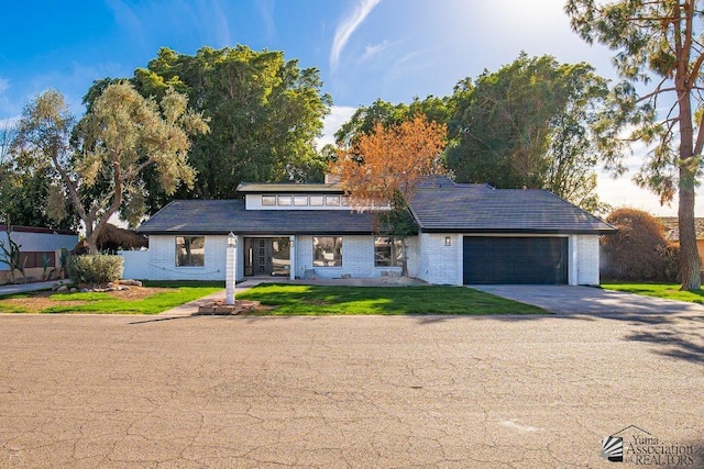 view of front of home with a garage, driveway, brick siding, and a front lawn