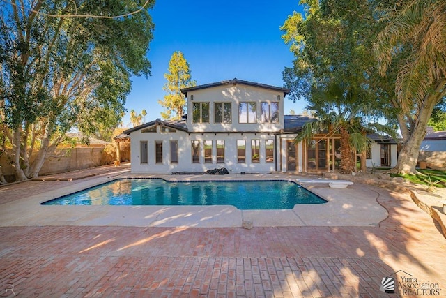 pool featuring a diving board, fence, and a patio