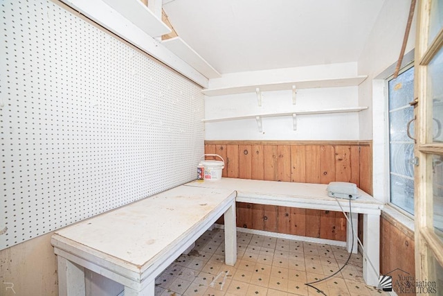 mudroom with light floors, wainscoting, and wooden walls