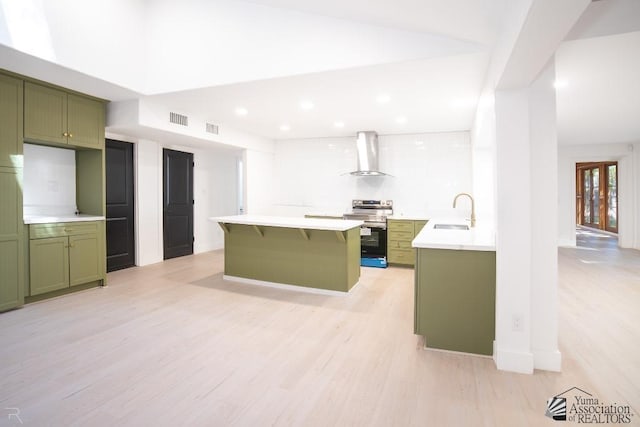 kitchen featuring light countertops, wall chimney range hood, green cabinetry, and stainless steel electric stove