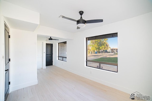 empty room featuring light wood finished floors, a ceiling fan, and baseboards