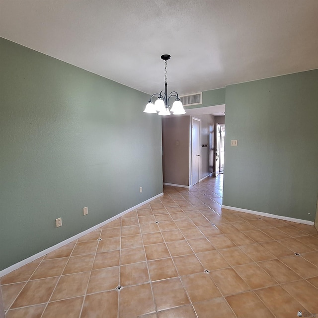 tiled empty room featuring a notable chandelier