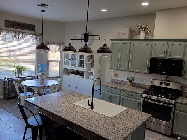 kitchen featuring sink, an island with sink, hanging light fixtures, and stainless steel range oven