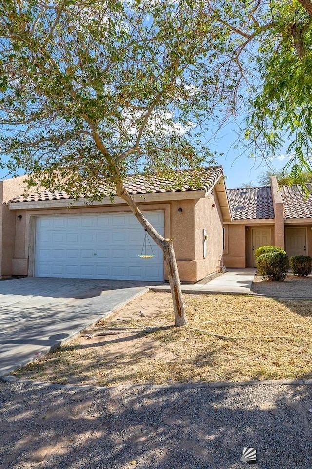 view of front of house featuring stucco siding, concrete driveway, an attached garage, and a tile roof