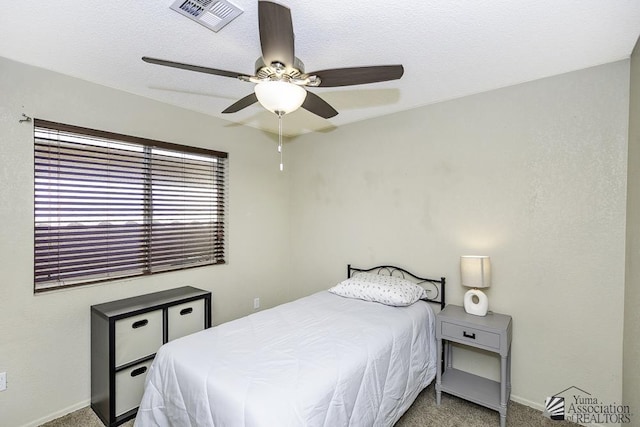 carpeted bedroom featuring a textured ceiling, baseboards, visible vents, and ceiling fan